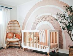 a baby's room with a crib, chair and potted plant