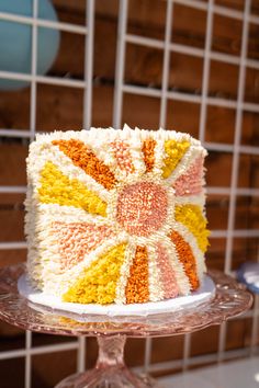 a cake that is sitting on top of a glass stand in front of a tiled wall