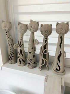 five ceramic cats sitting on top of a window sill