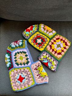 four crocheted squares sitting on top of a gray couch next to each other