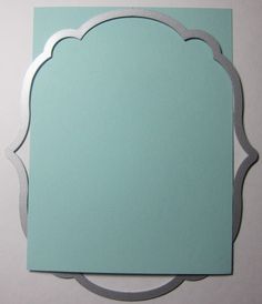 a blue paper with a silver border around it on a white surface and the corner is shaped like an arch