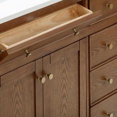 a close up of a wooden cabinet with drawers and knobs on the bottom drawer