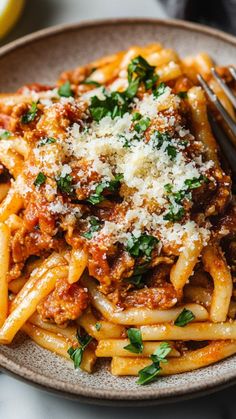 a plate of pasta with sauce and parmesan cheese on top, next to a fork