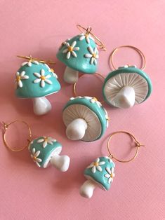 several small blue and white mushrooms are on a pink tablecloth with gold hoop earrings