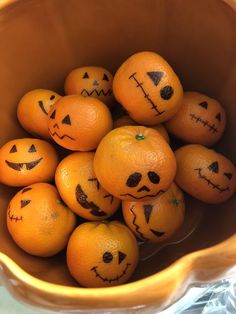 oranges with faces drawn on them in a bowl