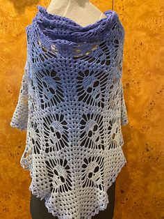 a blue and white crocheted shawl on a mannequin