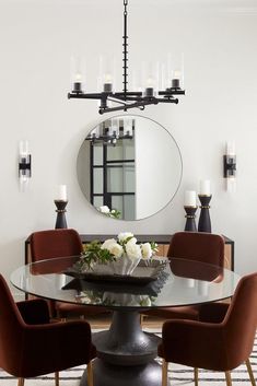 a dining room table with chairs around it and a mirror on the wall behind it