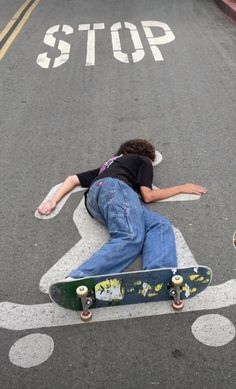 a man laying on the ground with his skateboard in front of him and another person standing behind him