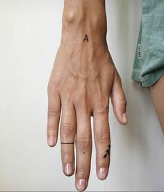 a person's left hand with a small tattoo on the middle part of it