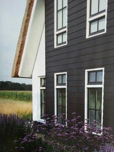 a black house with white windows and purple flowers