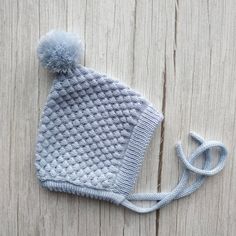 a crocheted hat with a blue pom - pom attached to it