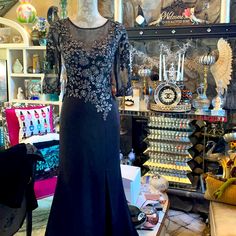 a dress on display in a store with lots of glassware and other items behind it