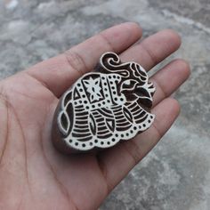 a hand holding a small metal object in it's left hand with designs on it