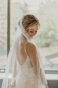 a woman standing in front of a window wearing a veil