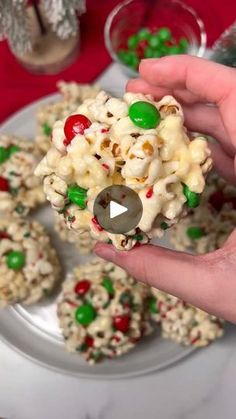 a person is holding up some candy popcorn balls on a plate with other snacks in the background