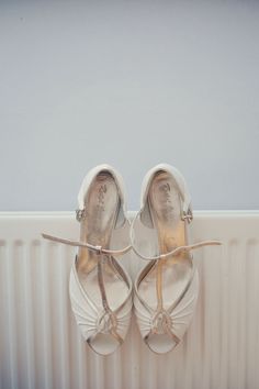 two pairs of white shoes hanging on the side of a radiator