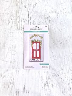 a card with a red door and vines on the front is in its package for sale