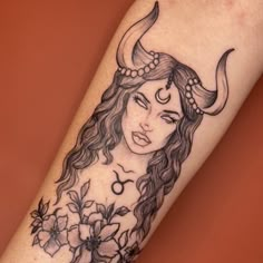 a woman with horns and flowers on her arm