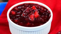 a white bowl filled with cranberry sauce on top of a red cloth