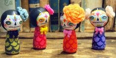 three small figurines with colorful hair and makeup on top of a wooden table