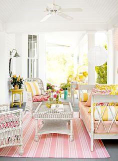 a living room filled with lots of furniture and flowers on top of a rug in front of a window