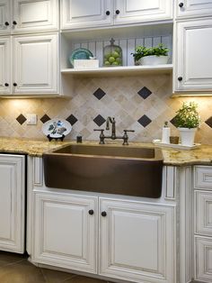 a kitchen with white cabinets and brown granite counter tops, an apron style sink in the center