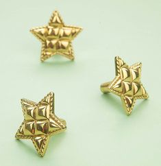 three gold star shaped rings on a green surface