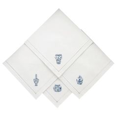 three white napkins with blue crest designs on them