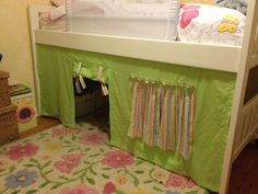 a child's bed with a green cover over the top and pink flowers on the bottom