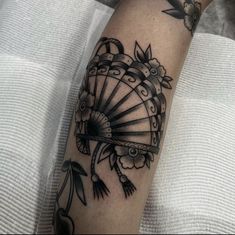 a woman's arm with a fan tattoo on it