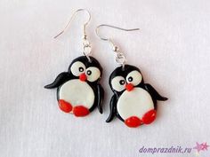 two small black and white penguins are hanging from silver earwires with red accents