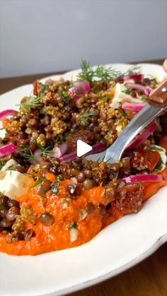 a white plate topped with food on top of a wooden table next to a knife and fork