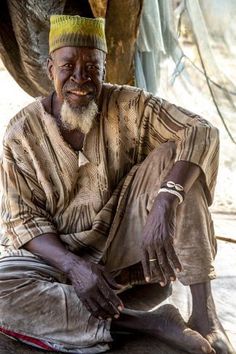 an old man sitting on the ground with his feet crossed