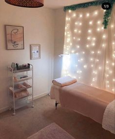 a bed room with a neatly made bed and lights on the window sill above it