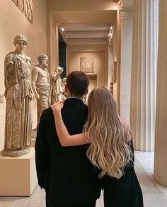 a man and woman standing in front of some statues