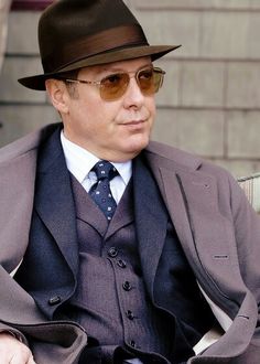 a man in a suit and hat sitting down