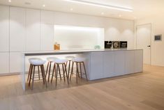 a kitchen with white cabinets and stools next to an island in the middle of the room