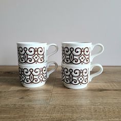 two white coffee mugs sitting on top of a wooden table next to each other