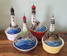 three bowls with small knitted lighthouses in them