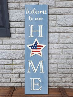 a wooden sign with the words welcome to our home and an american flag on it