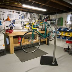 a bike is mounted to a metal pole in a garage with workbench and tools on the wall