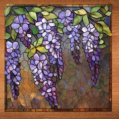 a stained glass window with purple flowers hanging from it's sides and green leaves