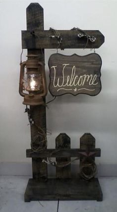 a wooden sign that says welcome with a lantern attached to it and some lights on the post