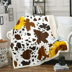 a brown and white cow print blanket with sunflowers on the back in front of a couch