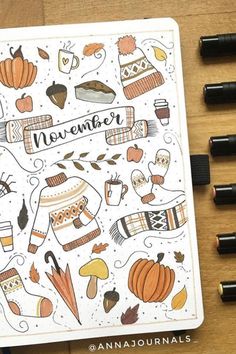 an open notebook with the words november surrounded by autumn doodles and pencils on a wooden surface