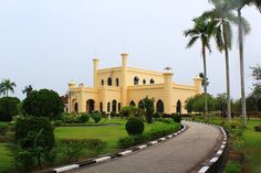 a large yellow building sitting on the side of a road next to lush green trees