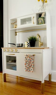 a kitchen with white cabinets and gold accents on the countertop, along with a potted plant