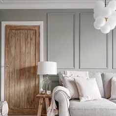 a living room filled with furniture and a white couch next to a wooden door on the wall