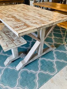 a wooden table with two benches on top of it in front of a blue rug