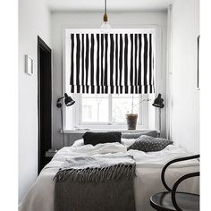 a bedroom with black and white striped roman shades on the window sill above the bed